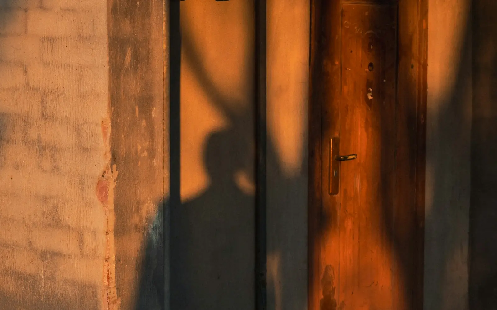 Porta de madeira iluminada pelo sol e cercada por sombras