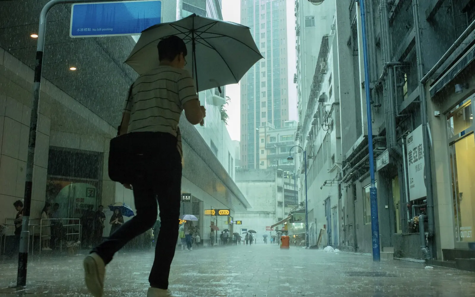 Pessoa atravessando uma rua urbana sob chuva intensa